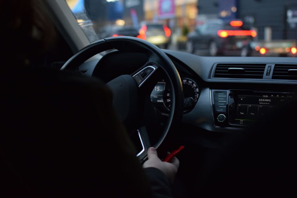 Interior view of a car dashboard while driving through Stockholm's city streets at night, capturing urban traffic lights.
